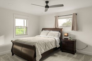 A bedroom with a bed, a nightstand, a ceiling fan, and a window with curtains. - Farm Views | 10min to Sight & Sound (Ronks)