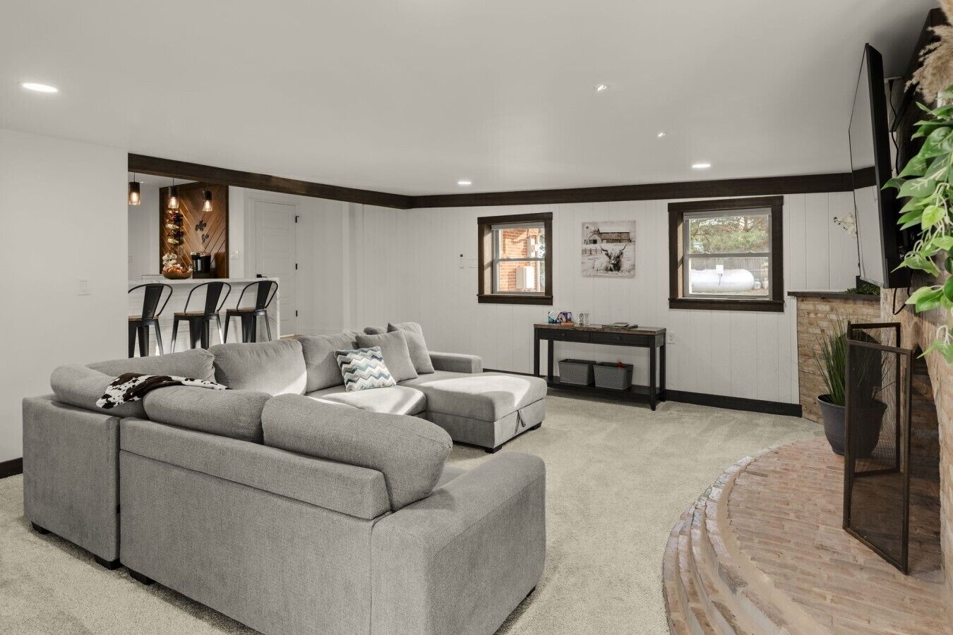 A living room with a grey sectional sofa, a small table, and a TV mounted on the wall.