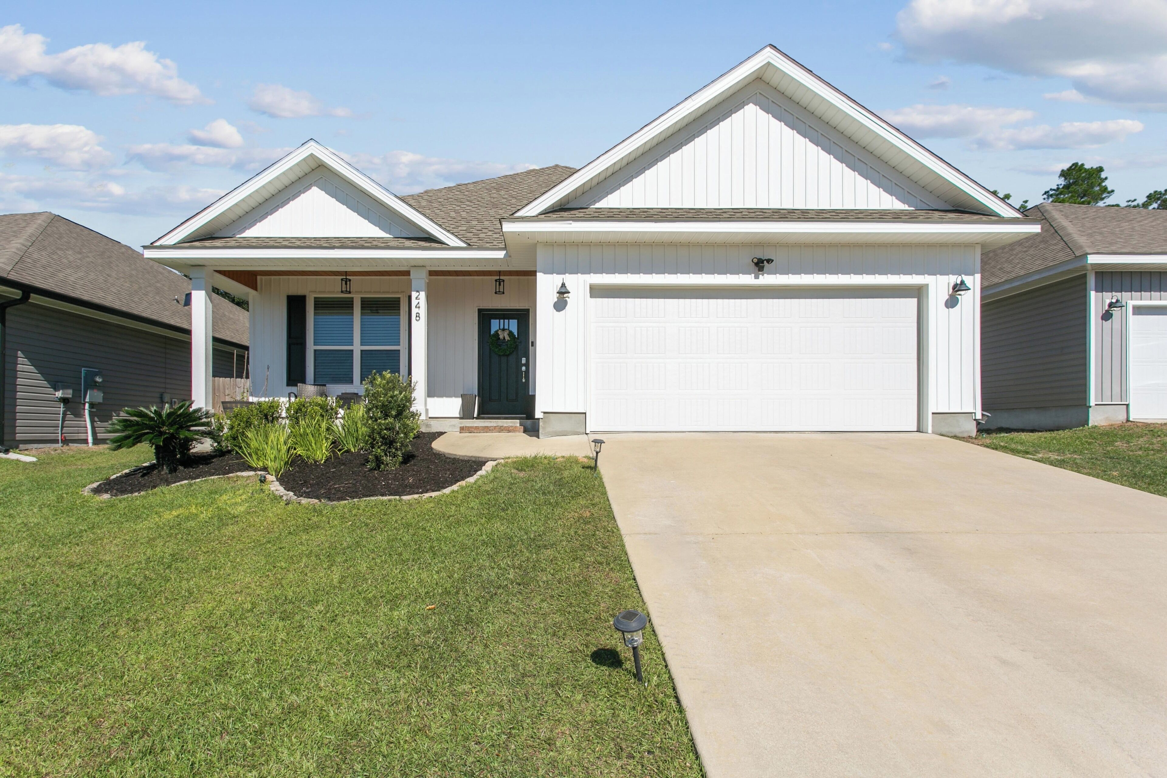 A two-story house with a front garage, a covered porch, and a well-maintained lawn.