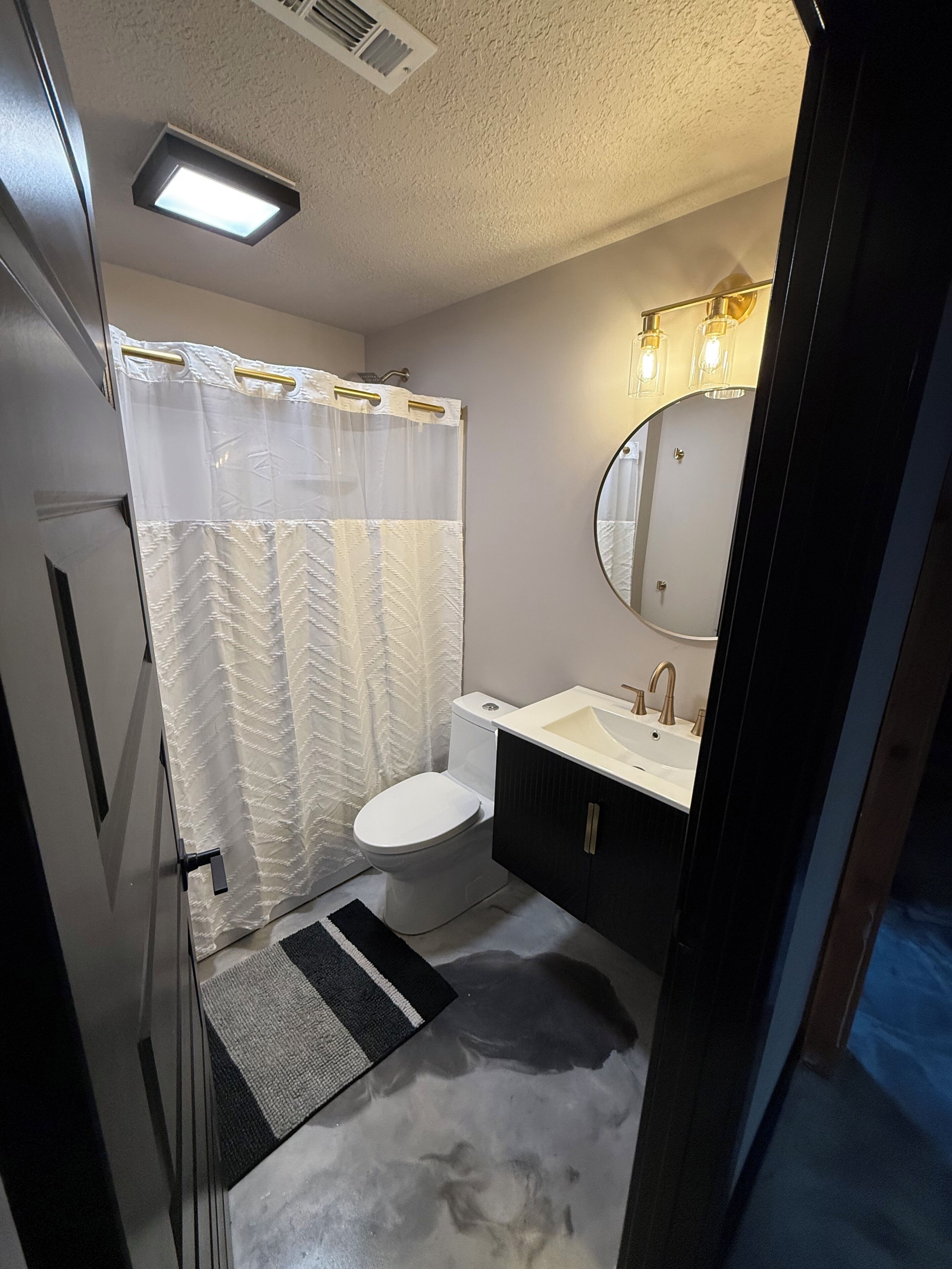 A bathroom with a toilet, sink, mirror, and shower curtain.