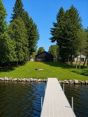 Un chalet au bord du lac, doté d’un quai s’avançant dans l’eau, et entouré d’une forêt dense.