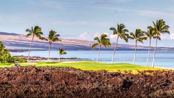 A golf course with a view of the ocean and mountains.
