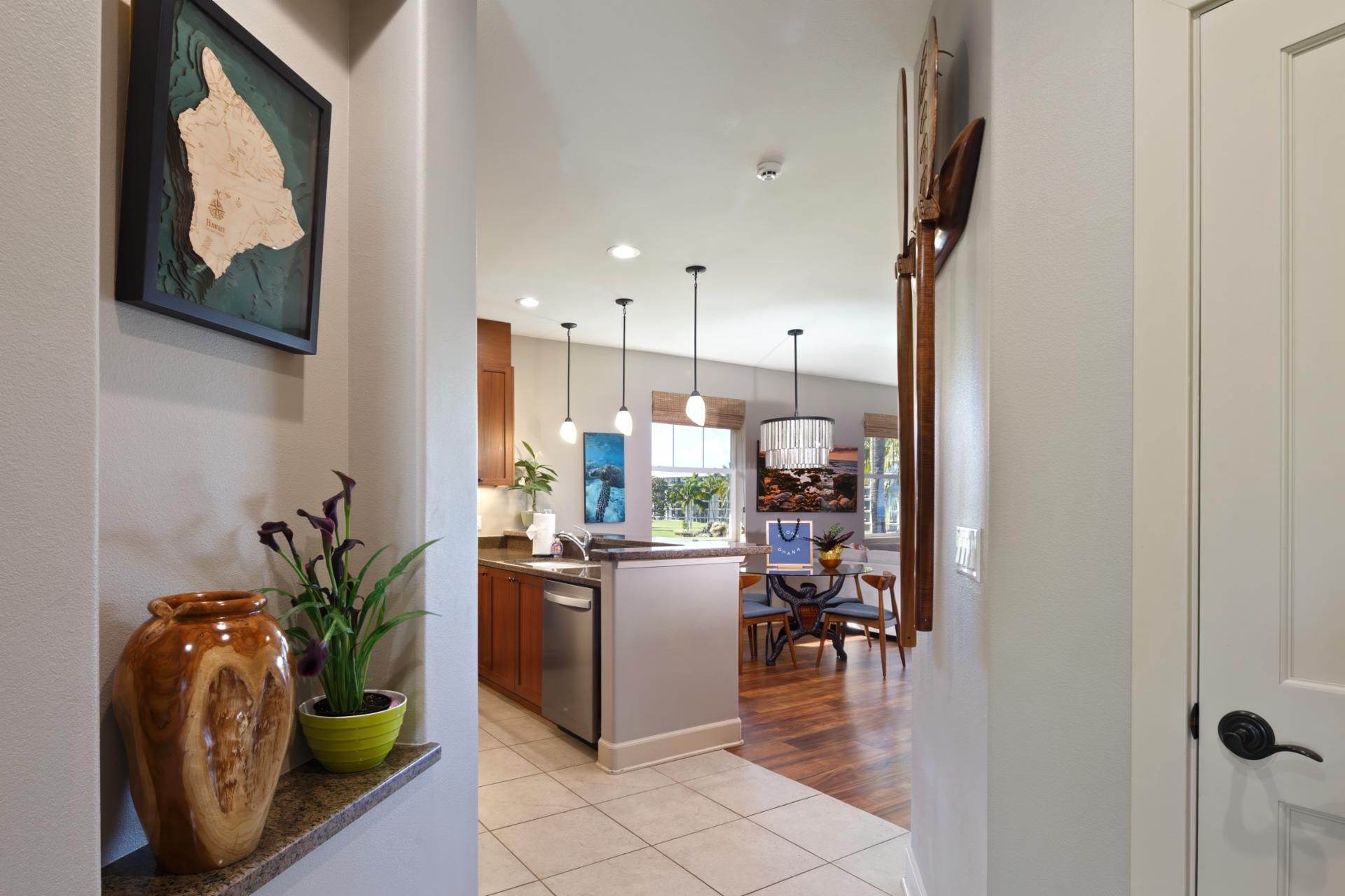 A hallway leading to a kitchen with a dining area, wooden cabinets, and a large map on the wall.