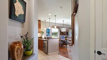 A hallway leading to a kitchen with a dining area, wooden cabinets, and a large map on the wall.