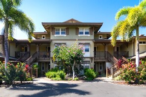 A multi-story hotel with a central courtyard, balconies, and tropical landscaping. - Halii Kai | Ocean View 2 BR | Car Incl. w/ 6+ Nights | HLI-7A by KBM (Waikoloa)