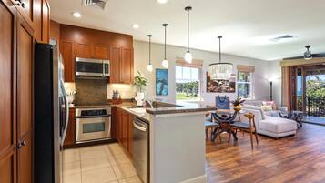 A modern kitchen with wooden cabinets, stainless steel appliances, and pendant lighting.