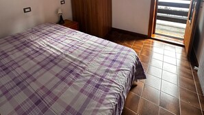 A bedroom with a bed, wardrobe, and a small shelf with items. - La Finestra Su Livigno, House with a View (Teola)