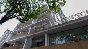 A modern building with multiple floors, large windows, and balconies with wooden railings. - Studio com Varanda a 280m do Metr Vila Madalena (São Paulo)