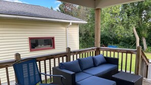 En overdækket terrasse med fletmøbler, en stol og et bord.