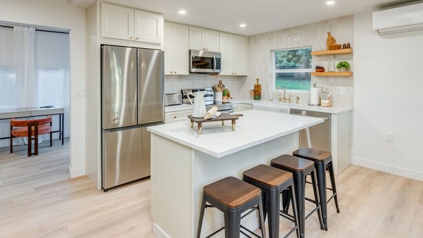 A modern kitchen with a central island, stainless steel appliances, and bar stools. - SPA&Sauna Retreat-Serene Setting, picnic/fireplace, Enjoy with the whole family! (Vancouver)