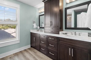 A bathroom with dark wooden cabinets, a white countertop, and a large mirror. - Cobia Cabana (Destin)