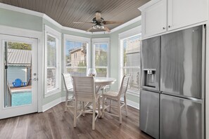 A kitchen with a stainless steel refrigerator, a ceiling fan, and a dining area with a table and chairs. - Cobia Cabana (Destin)