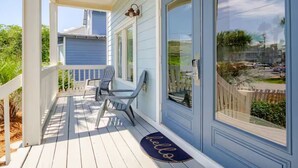 A covered porch with two chairs and a bench, a 'hello' mat, and a view of the neighborhood. - Cobia Cabana (Destin)
