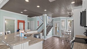 A spacious kitchen with a granite countertop, a dishwasher, and a dining area with a table and chairs. - Cobia Cabana (Destin)