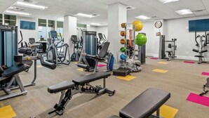 Ein Fitnessstudio mit verschiedenen Trainingsgeräten, darunter Laufbänder, Kraftgeräte und Kurzhanteln.