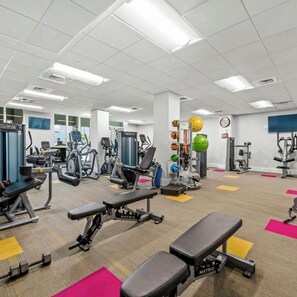 Uma academia com diversos equipamentos de exercícios, incluindo esteiras, aparelhos de musculação e pesos livres.