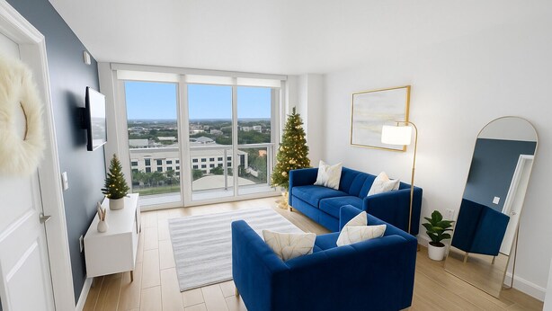 Ein modernes Wohnzimmer mit einer blauen Sofagarnitur, einer Stehlampe, einem kleinen Weihnachtsbaum und einem großen Fenster mit Blick auf die Stadt.