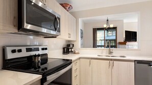 Eine moderne Küche mit Edelstahlgeräten, hellem Holzkorpus, Backofen und Geschirrspüler.