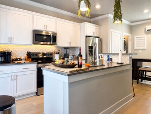 A modern kitchen with white cabinetry, stainless steel appliances, and a central island. - Heart of Northshore Townhouse (Chattanooga)