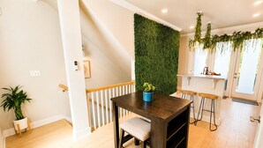 Une cuisine moderne avec une table en bois, un mur vert et un escalier.