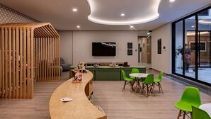 Een modern interieur met een gebogen houten constructie, een bar, groene stoelen en een groot raam.
