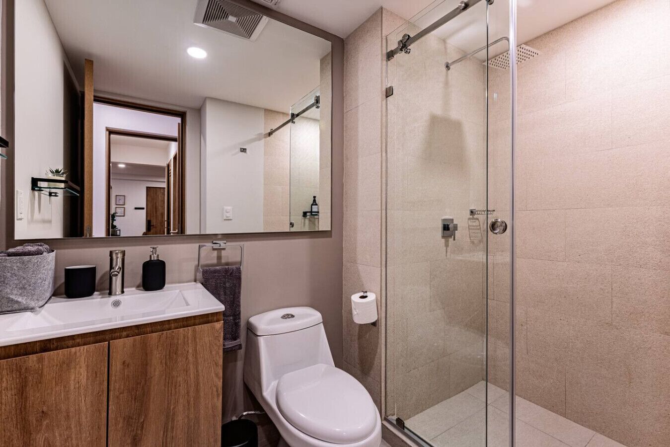 Une salle de bain moderne avec une douche à parois de verre, un meuble-lavabo en bois et des toilettes blanches.