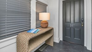 A dark grey door with the number 103, a woven bench with a lamp and a book, and grey blinds. - Walk to Coffee, Dining & Campus | Historic Studio (Columbia)