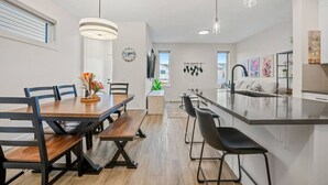 Een moderne keuken met een centraal eiland, een houten eettafel en barstoelen.