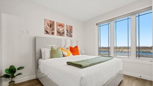 Een moderne slaapkamer met een groot bed, uitzicht op de omgeving en kunst aan de muur.