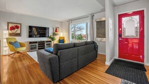 Ett modernt vardagsrum med en grå soffa, en gul fåtölj och en röd dörr.