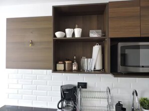 Una cocina moderna con armarios de madera, microondas integrado y cafetera.