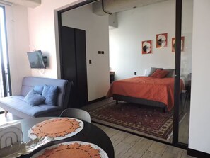 Un dormitorio moderno con una cama, un sofá y un televisor montado en la pared.