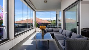 A modern balcony with a glass door, a glass table, and a gray sofa. - Gorgeous home in Podstrana (Podstrana)