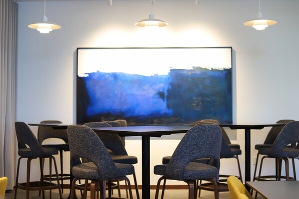 Un salón de conferencias con una gran mesa, seis sillas y un cuadro abstracto de gran tamaño en la pared.