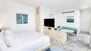 Een hotelkamer met een bed, een bureau, een stoel, een televisie en kunstwerken aan de wanden.
