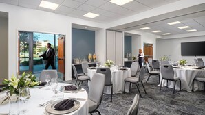 Une salle de conférence équipée de tables rondes, de chaises et d’un grand écran.