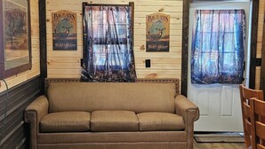A cozy cabin interior with a wooden ceiling, a sofa, and deer-themed decor.