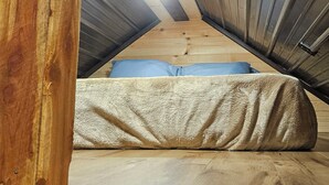 A room with a sloped ceiling, wooden beams, and a metal door.