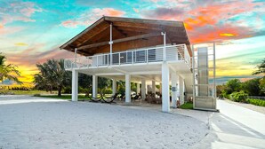 Ein Gebäude direkt am Strand mit einer überdachten Terrasse, Sitzgelegenheiten im Freien und Blick auf den Ozean.