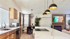 Une cuisine moderne dotée d’un grand îlot central, de meubles en bois et de luminaires suspendus.