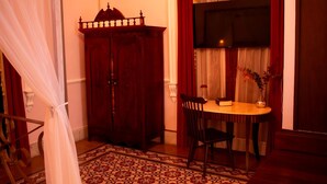 A room with a wooden cabinet, a table with two chairs, and a TV mounted on the wall. - La Casa Rosa Imperial (Mérida)