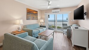 Ein Hotelzimmer mit Balkon, Flachbildfernseher, Deckenventilator und einem Gemälde.