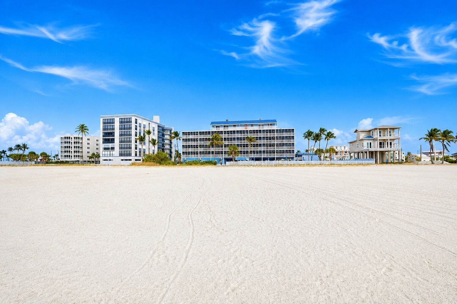 A beachfront hotel with multiple buildings, including a large hotel structure and a smaller building with a balcony.