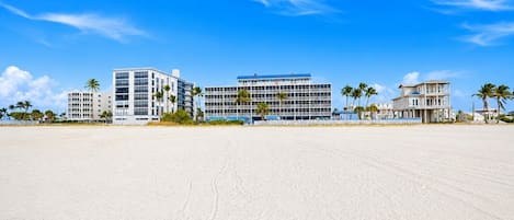 A beachfront hotel with multiple buildings, including a large hotel structure and a smaller building with a balcony.