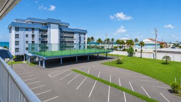 A multi-story hotel with a parking area and a pedestrian bridge.