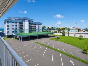 A multi-story hotel with a parking area and a pedestrian bridge.