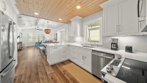 Een moderne keuken met witte kasten, houten vloeren en roestvrijstalen apparatuur.