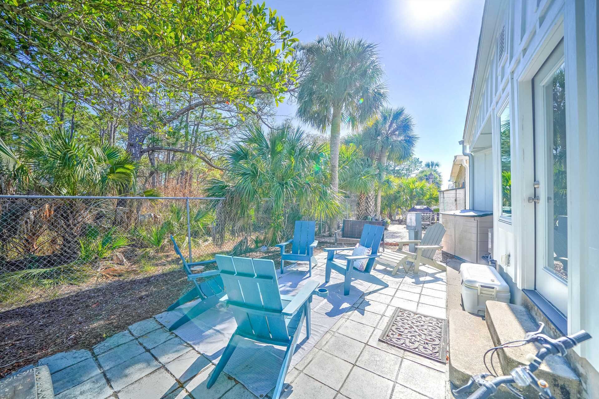 A patio with outdoor seating, a fence, and a building with a door.