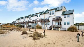 A beachfront hotel with multiple balconies and a sandy beach area.