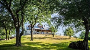 A house with a large porch, surrounded by trees and a grassy hill. - The Redwood Estate - Events on 25 Acres of Serenity (Aubrey)